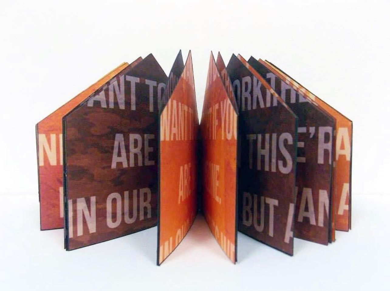 Handmade book structure with polygon shaped pages printed with white text on brown and orange pages.