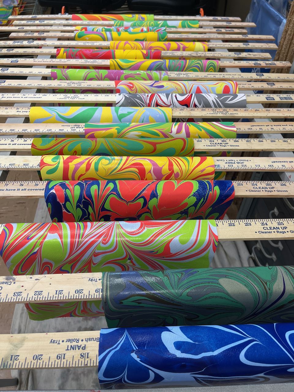 Freshly marbled papers drying on yard sticks.